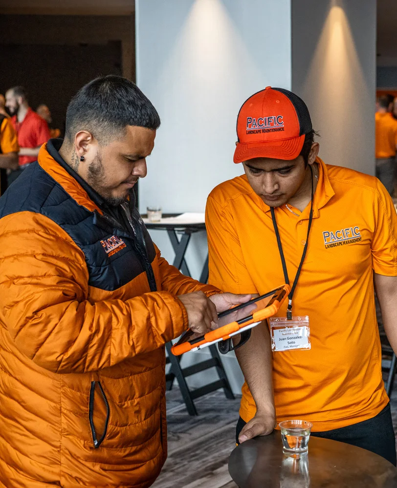Two employees wearing orange jackets and shirts labeled 